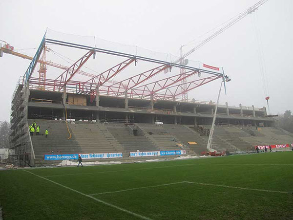 Stahlkonstruktion des Stadiondaches, im Hintergrund sind Baukräne zu sehen